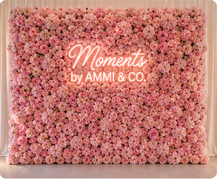 Blush pink flower wall with Moments by AMMI & Company LLC logo