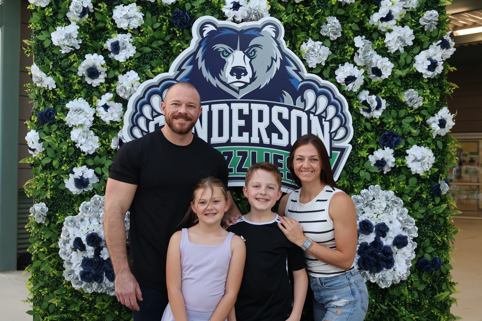 Family celebrating Grizzly Night at the Gunderson floral greenery wall