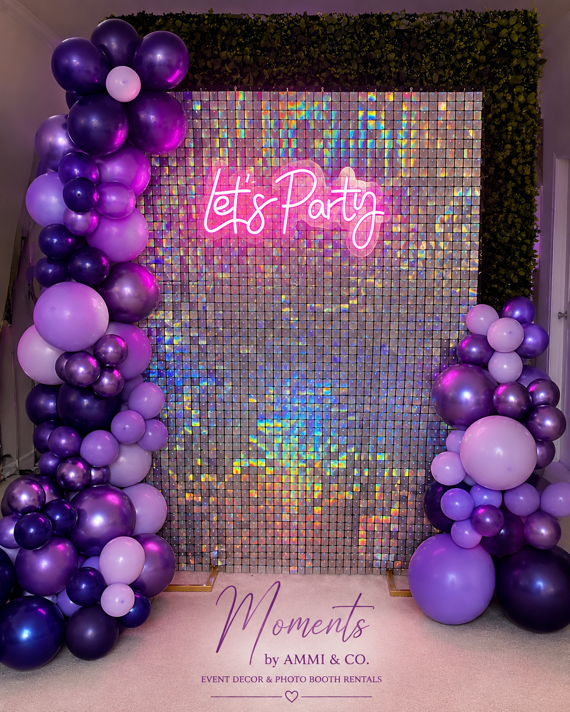 Silver shimmer wall with purple balloon garland and pink Let’s Party neon sign